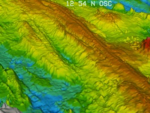 The sea floor’s texture near the East Pacific Rise, a mid-ocean ridge in the Pacific Ocean, shows alternating ridges and valleys, indicating ancient highs and lows of volcanic activity. A new study examining the depth variations, or bathymetry, of the Southern East Pacific Rise, along with information about present-day volcanic eruptions, finds that the intensity of volcanic activity at deeply submerged mid-ocean ridges waxes and wanes on a roughly 100,000-year cycle. Credit: Haymon et al., NOAA-OE, WHOI. 